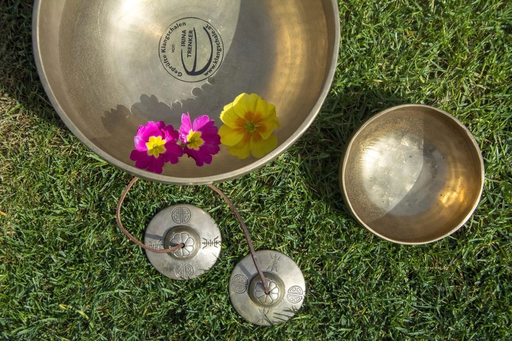 Overhead view of a set of Tibetan singing bowls and mallets on a plain surface.